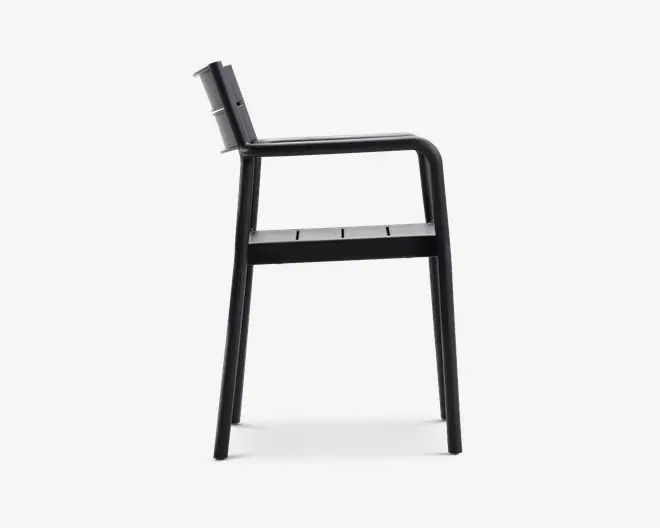 Sidevisning af en moderne stol med et minimalistisk design og mat sort finish. Stolen har et let skråt ryglæn, lige armlæn og et sæde med lameller. Benene er lige og robuste, hvilket giver stabil støtte. Det samlede udtryk er stilrent og moderne, velegnet til både indendørs og udendørs brug.