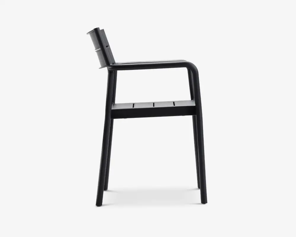 Sidevisning af en moderne stol med et minimalistisk design og mat sort finish. Stolen har et let skråt ryglæn, lige armlæn og et sæde med lameller. Benene er lige og robuste, hvilket giver stabil støtte. Det samlede udtryk er stilrent og moderne, velegnet til både indendørs og udendørs brug.