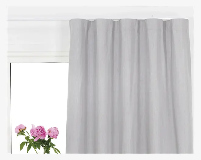 Lys gråt stof med en diskret tekstur og jævnt fordelte folder øverst, som giver et samlet udtryk. Materialet virker mellemtykt og giver let lysfiltrering samtidig med, at det bevarer privatlivet. Gardinet hænger lige og glat med et blødt fald.