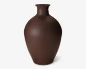 Høj, rund vase med en smal hals og udadgående kant, udført i en mat mørkebrun farve. Overfladen har en let tekstureret finish, hvilket giver et naturligt og jordnært udtryk. Vasen er uden dekorationer og fremhæver dens enkle og elegante form.