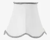 Hvid lampeskærm med udvidet, bølget bundkant og diskret sølvkant langs toppen og bunden. Stoffet har en let tekstur, hvilket giver et klassisk og elegant udtryk, der passer til traditionel eller vintage-inspireret indretning.