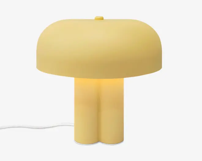 Lysegul lampe med svampeformet, bred og afrundet skærm, todelt cylindrisk fod, lille afbryder på toppen og synlig hvid ledning.