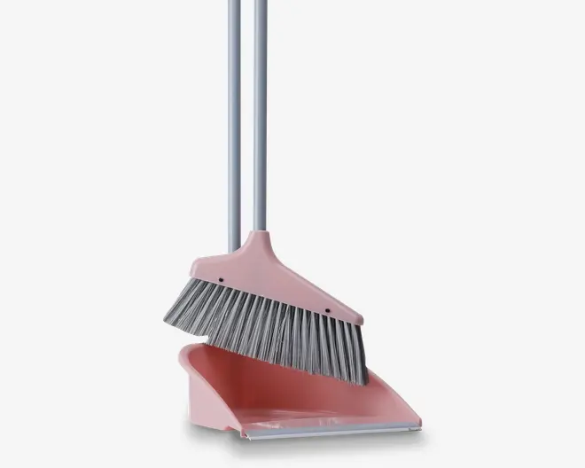 Et rengøringssæt bestående af en lyserød fejebakke og en matchende kost med lange sølvfarvede håndtag. Kosten har tætte, skrå grå børster, der effektivt fejer snavs, og fejebakken har en flad kant for nem opsamling af affald. Kosten passer perfekt ned i fejebakken for kompakt opbevaring.