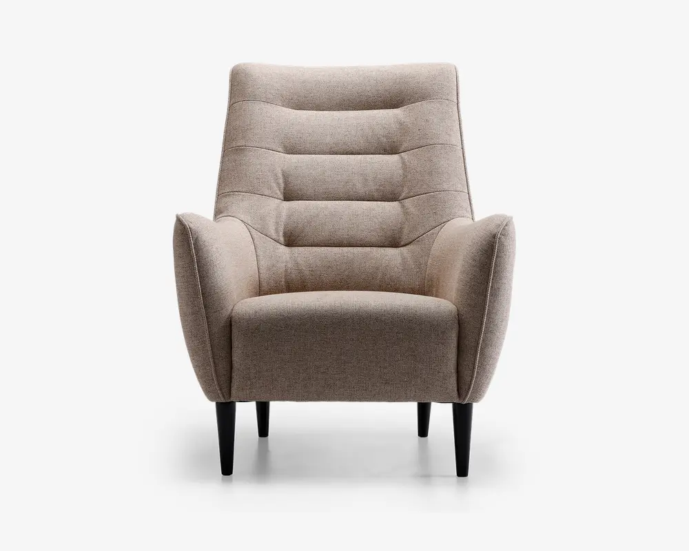 Frontvisning af en moderne lænestol med lysebeige stofbetræk. Stolen har en høj, let tilbagelænet ryg med vandrette kanalsyninger, der giver ekstra komfort og stil. Armlænene er vinklet udad og skaber et moderne udtryk. Sædepuden er tyk og blød, og stolen står på fire koniske sorte træben.