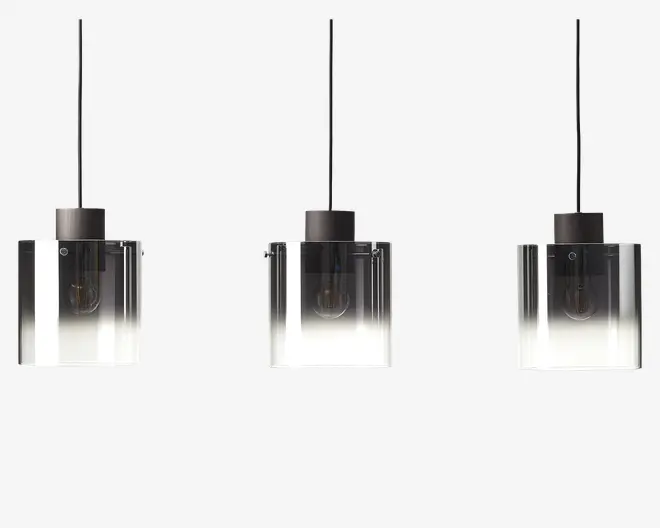 Sæt med tre pendellamper med firkantede, klare glasskærme, der har en gradient fra gennemsigtig i toppen til mat hvid i bunden. Hver lampe har en sort metalfatning og sort ledning til ophæng. Pærerne er synlige gennem glasset, hvilket giver et moderne og minimalistisk udtryk.