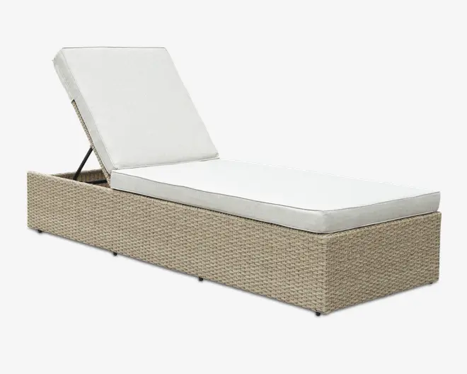 Rektangulær udendørs liggestol med en flettet rattanbase i lys beige farve. Stolen har en tyk, hvid polstret siddehynde og et justerbart ryglæn, som også er polstret i hvid, og kan indstilles i flere liggepositioner. Designet er moderne og minimalistisk, velegnet til terrasse eller ved poolen.