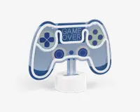 En dekorativ LED-lampe formet som en videospil-controller med blå og hvide farver. Lampen har knapdetaljer og teksten 'GAME OVER' oplyst øverst i midten. Den er monteret på en rund, hvid base.