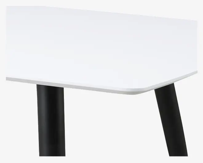 Nærbillede af et bordhjørne med en glat, hvid rektangulær bordplade med blødt afrundede kanter. Bordet understøttes af solide, cylindriske sorte ben, der er let skråtstillede, hvilket giver et moderne og minimalistisk udtryk.