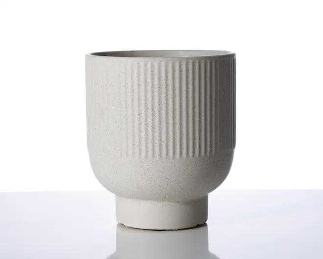 Et lyst beige keramikkar med mat finish. Den øverste halvdel har lodrette rillede teksturer, mens den nederste halvdel er glat og rund. Bunden er cylindrisk og en smule smallere end selve karret, hvilket giver stabilitet. Designet er minimalistisk og moderne.