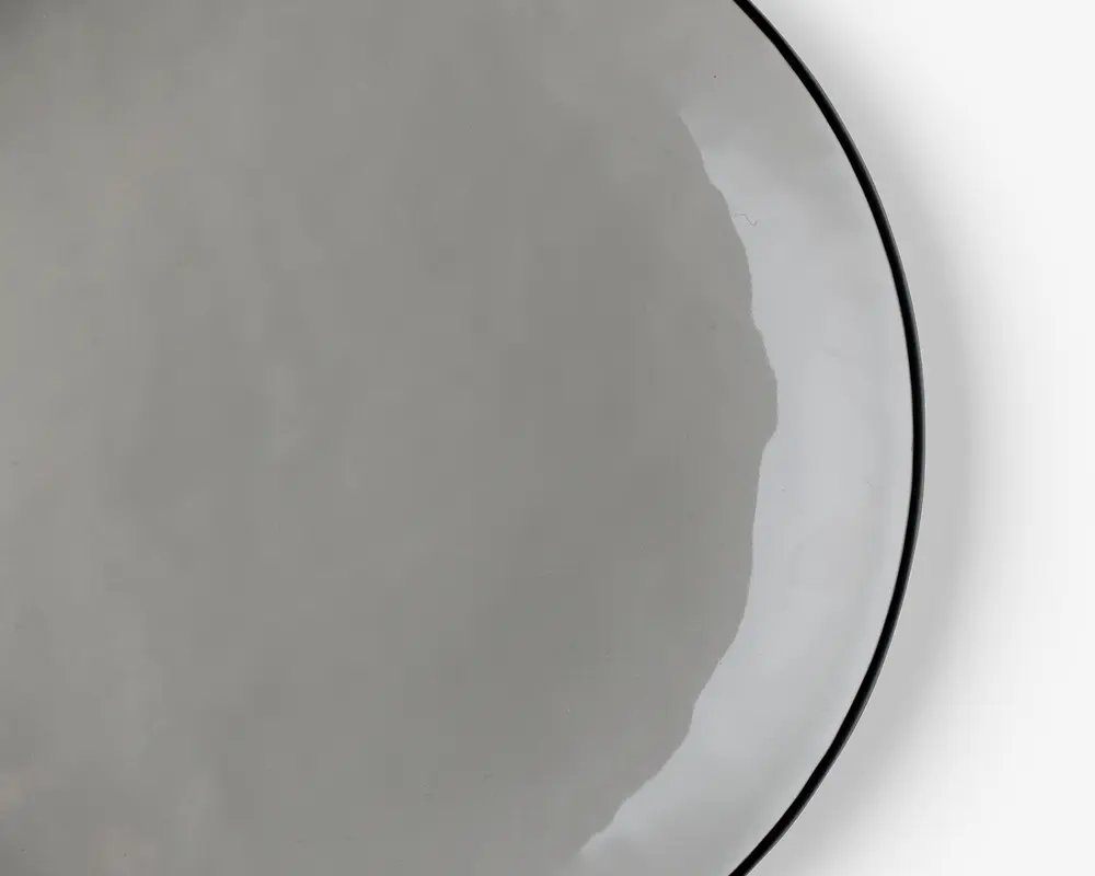 Et nærbillede af et enkelt, rundt, tyndt og let gennemsigtigt fladbrød med en glat overflade og ujævne kanter, placeret på en hvid tallerken. Fladbrødet ser blødt og fleksibelt ud.