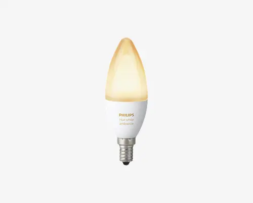 En LED-pære formet som et stearinlys med matteret spids, der udsender et varmt hvidt lys. Pæren har en metalgevindfatning og en hvid krop med teksten 'PHILIPS Hue white ambiance' trykt i guld. Designet er slankt og moderne, velegnet til dekorative lamper.