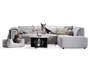 Lysegrå polstret hjørnesofa med chaiselong på højre side, enkle firkantede hynder, lave sorte ben og neutrale pyntepuder, stylet med et rundt sofabord, vase med blomster, stearinlys og bløde tæpper; vist med to hunde for størrelsesfornemmelse.