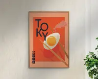 Indrammet plakat med en kraftig orange baggrund, der viser et stiliseret spejlæg, som holdes af et par træspisepinde. Ordet 'TOKYO' står med store, mørkeblå bogstaver, hvor 'O'et delvist overlapper ægget. Dekorativ damp og japanske tegn tilføjer visuel interesse. Rammen er af lyst træ, og plakaten har et moderne, minimalistisk design.