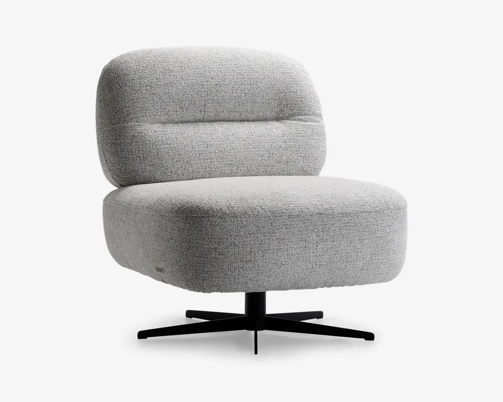Armløs loungestol med bredt, kraftigt polstret sæde og ryglæn, betrukket med lysegråt tekstureret stof. Stolen har en rundet, moderne silhuet og står på en sort metal drejefod med fire ben for stabilitet.