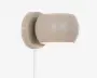 Væghængt lampe med en glat, rund skærm i mat beige og matchende cirkulær base. Lampen har et minimalistisk design med en åbning, der vender nedad for fokuseret belysning. En hvid ledning går ud fra bunden af basen.