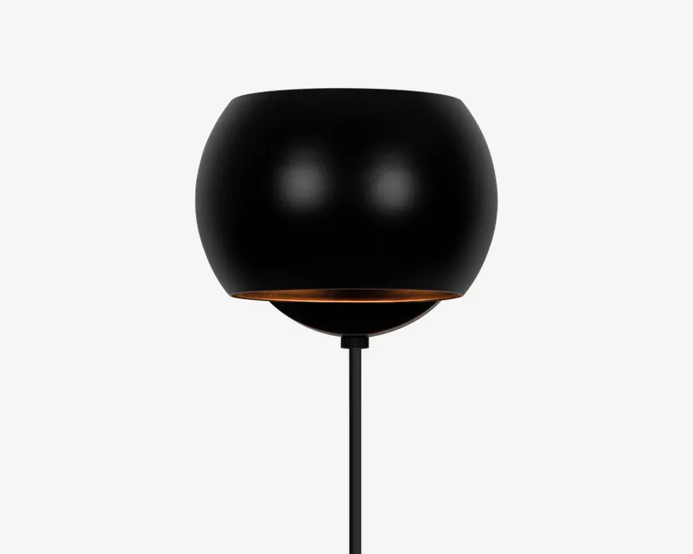 En moderne lampe med en mat sort, rund skærm, der har en let åben bundkant med en diskret gylden indvendig detalje. Lampen har et slankt, minimalistisk design med en lige, tynd sort stander.