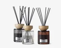 Sæt med tre duftpinde i riflede glasbeholdere, hver i en forskellig farve: sort, klar og ravfarvet. Hver diffuser har et lyst trælåg og flere sorte pinde til at sprede duften. Beholderne har et moderne, elegant design med en metallabel på forsiden.