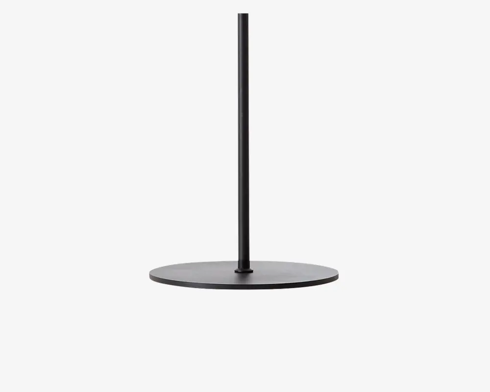Et slankt, minimalistisk stativ lavet af mat sort metal med en rund, flad base og en enkelt lodret stang i midten. Designet er enkelt og moderne med rene linjer og en solid konstruktion.