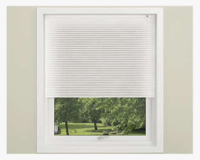 Hvid plisseret vinduesafdækning, delvist sænket, med jævnt fordelte vandrette folder. Gardinet passer præcist inden for en hvid vinduesramme og lader naturligt lys komme ind gennem den nederste, åbne del. Materialet virker let og giver privatliv, samtidig med at noget lys slipper igennem.