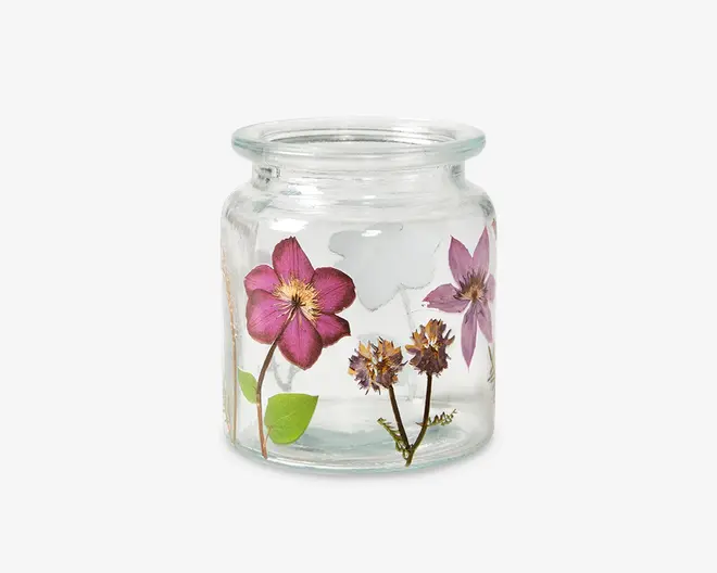 Klar glasbeholder med bred åbning og kort hals, dekoreret med indstøbte pressede lilla og lyserøde blomster samt grønne blade. Blomsterdesignet går hele vejen rundt om glasset og giver det et fint og dekorativt udtryk.