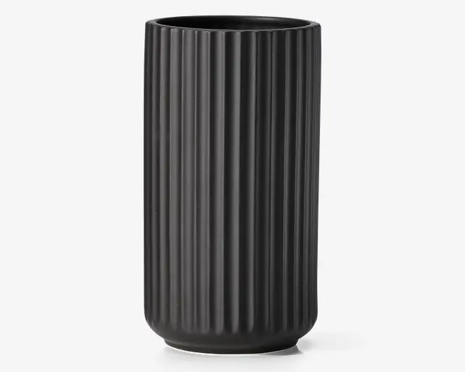 Høj, mat sort cylindrisk beholder med lodrette riller, åben top og let afrundet bund.