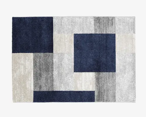 Rektangulært tæppe med et moderne geometrisk mønster bestående af store blokke og rektangler i marineblå, lysegrå, mellemgrå og offwhite. Designet er symmetrisk, og farverne er arrangeret i et balanceret, gitterlignende layout, hvilket giver tæppet et stilfuldt og nutidigt udtryk. Overfladen ser blød og luftig ud.