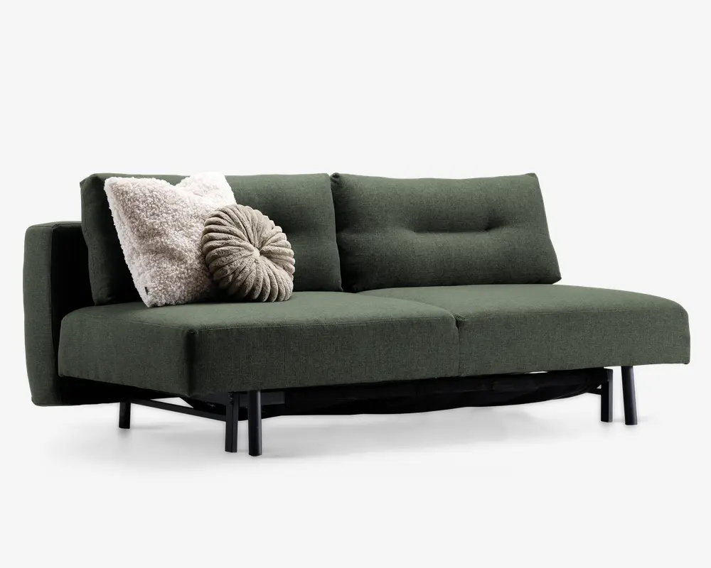En moderne sofa med mørkegrønt betræk og minimalistisk design, med rene linjer og sorte metalben. Sæde- og ryghynderne er tykke og bløde, hvilket giver god komfort. Sofaen er pyntet med to dekorative puder: en stor, fluffy, cremefarvet firkantet pude og en rund, plisseret, lysebrun pude, som tilføjer tekstur og visuel interesse.