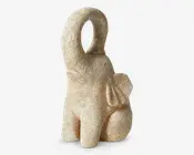 En dekorativ elefantfigur med en tekstureret, stenlignende overflade i en naturlig beige farve. Elefanten sidder med snablen løftet højt i en buet position, hvilket ofte anses som et symbol på held. Figuren har afrundede former, markante ører og et enkelt, minimalistisk design uden indviklede detaljer.