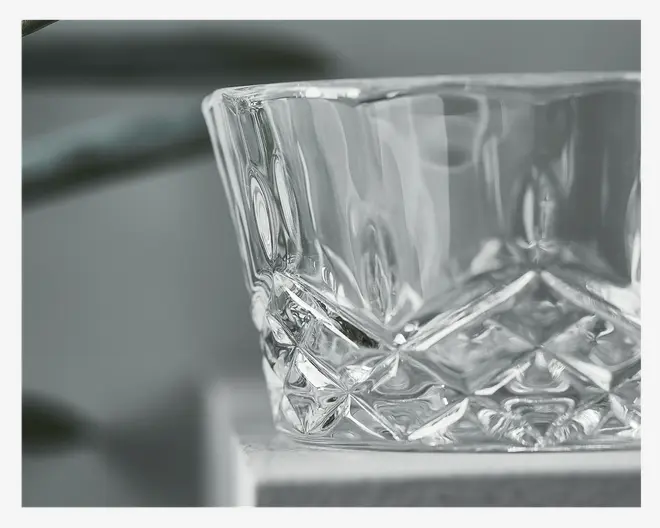 Klar glasskål med facetslebet, diamantmønster på den nederste halvdel, hvilket giver et tekstureret og elegant udseende. Kanten er glat og let udadbuet. Glasset er tykt, hvilket antyder holdbarhed og en eksklusiv fornemmelse.