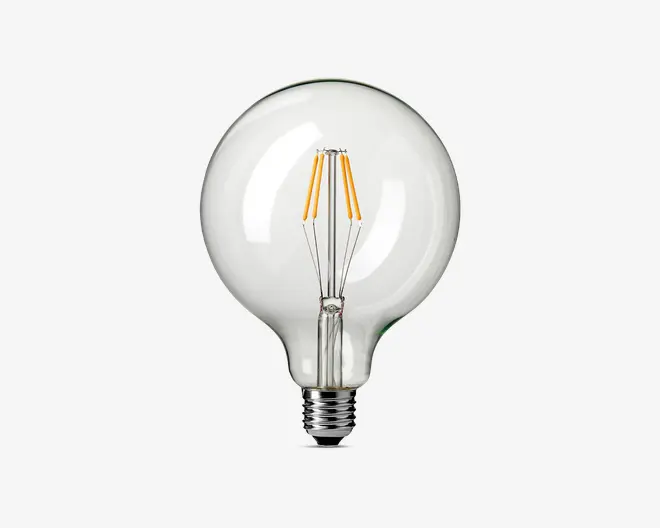 Klar glaspære med stor, rund form og synlige LED-filamenter, der er arrangeret lodret indeni. Pæren har en standard skruefatning og en glat, blank overflade, så de indvendige komponenter er lette at se. Designet er både moderne og minder om vintage-stil pærer, velegnet til dekorativ belysning.