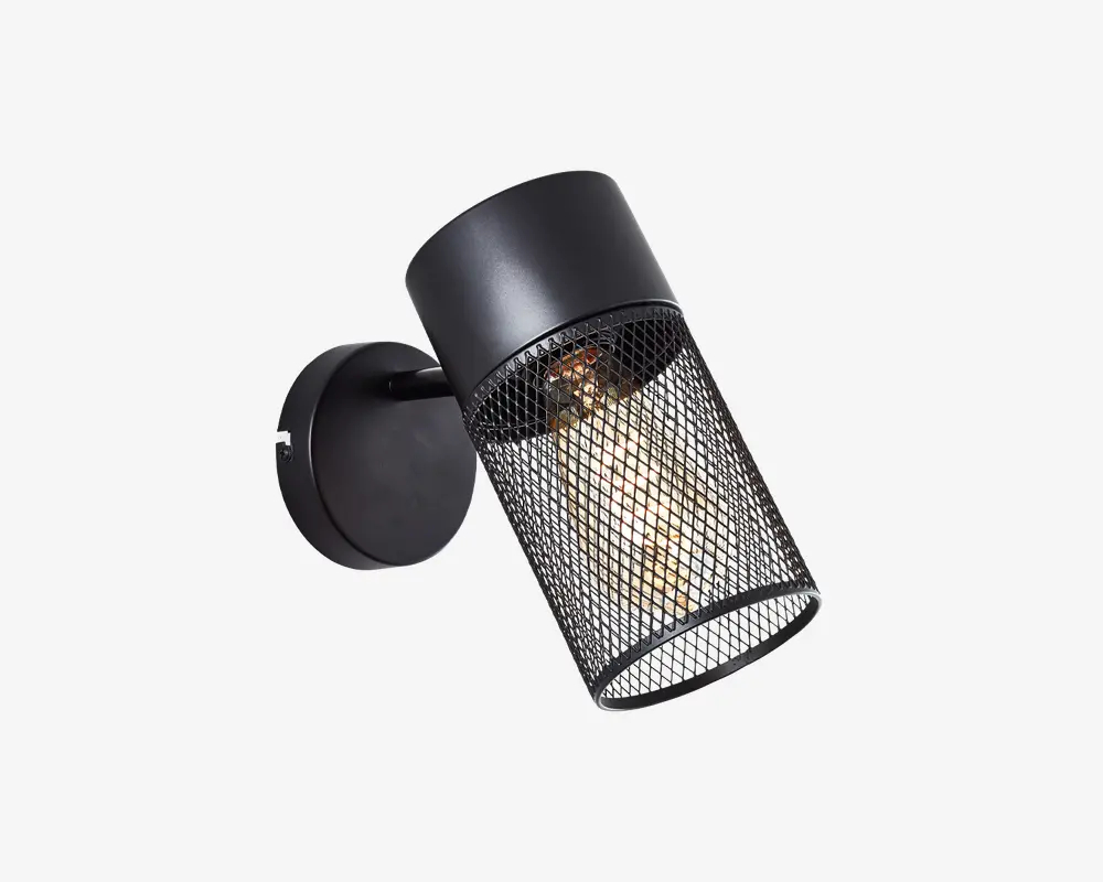 Væghængt lampe med rund sort base og justerbar arm. Lampens hoved har et cylindrisk sort metalhus med et netgitter, så pæren indeni er synlig. Designet har et industrielt udtryk, og netgitteret giver både beskyttelse og et dekorativt element, samtidig med at det spreder lyset.