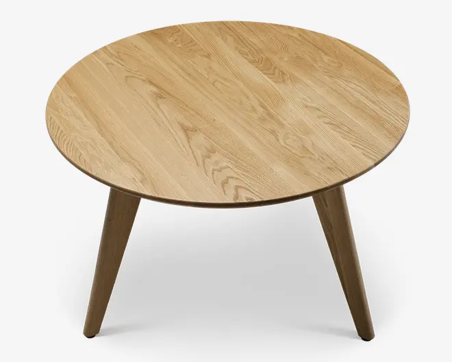 Rundt bord med en glat, lys egetræsfinish. Bordpladen har synlige naturlige åremønstre i træet, og bordet står på tre let skrå, solide ben, der også er lavet af matchende eg. Designet er minimalistisk og moderne med rene linjer og et varmt, naturligt udtryk.