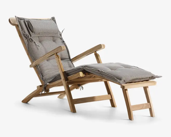 Liggestol i træ med tilhørende fodskammel, begge med tykke, polstrede hynder i sort-hvidt nålestribet mønster. Stolen har høj ryg, skrå armlæn og en aftagelig hovedpude for ekstra komfort. Stellet er lavet af lyst træ med en naturlig finish, og hynderne er fastgjort med bånd.