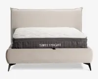 En tyk, blød madras med quiltet hvid top og mørkegrå sidepanel, hvor mærket 'SWEETNIGHT' står med store hvide bogstaver. Madrassen har en tekstureret overflade med diamantmønster for ekstra komfort og åndbarhed. Den er placeret på en moderne, polstret sengegavl med lyst beige stof og sorte skrå ben.