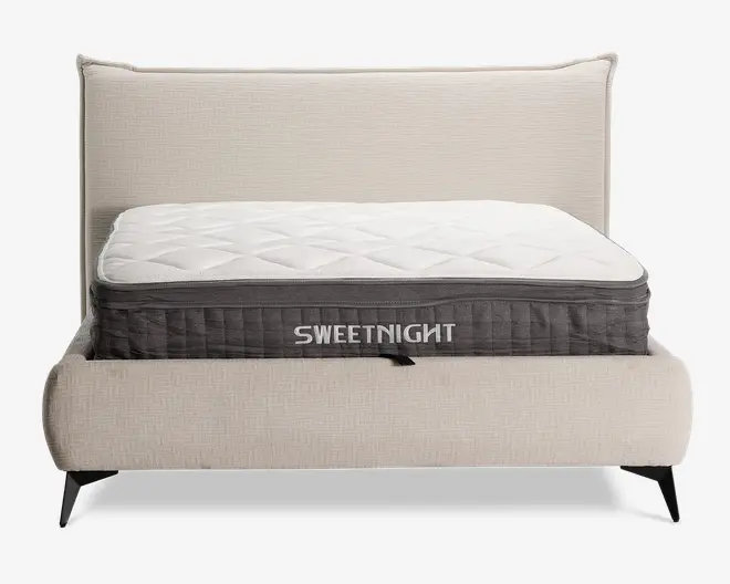 En tyk, blød madras med quiltet hvid top og mørkegrå sidepanel, hvor mærket 'SWEETNIGHT' står med store hvide bogstaver. Madrassen har en tekstureret overflade med diamantmønster for ekstra komfort og åndbarhed. Den er placeret på en moderne, polstret sengegavl med lyst beige stof og sorte skrå ben.