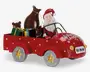 Festlig dekorationsfigur med julemanden, der kører en rød bil med hvide prikker og teksten 'Merry Christmas' på motorhjelmen. Bilen har sølvfarvede hjul med gyldne stjerner og en nummerplade foran med teksten 'Ho Ho Ho'. Bagpå er der farverige indpakkede gaver, en brun sæk og to brune rensdyrfigurer.