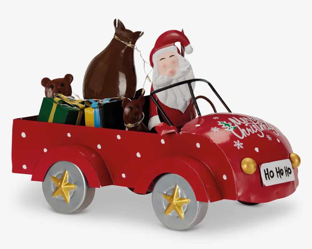 Festlig dekorationsfigur med julemanden, der kører en rød bil med hvide prikker og teksten 'Merry Christmas' på motorhjelmen. Bilen har sølvfarvede hjul med gyldne stjerner og en nummerplade foran med teksten 'Ho Ho Ho'. Bagpå er der farverige indpakkede gaver, en brun sæk og to brune rensdyrfigurer.