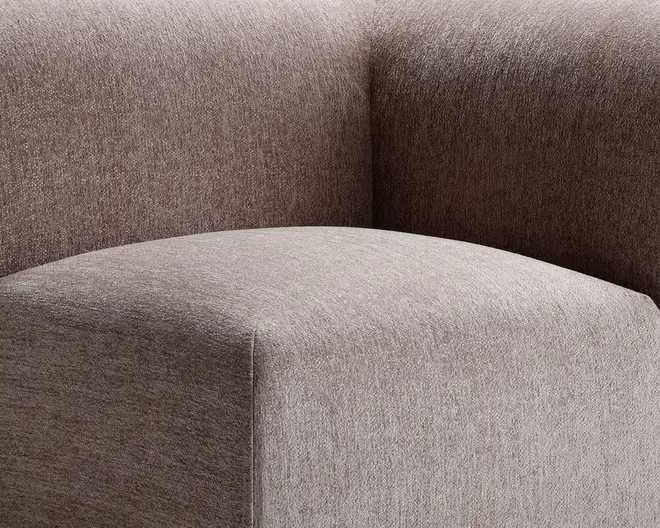 Nærbillede af et møbel betrukket med et tekstureret, taupefarvet stof. Billedet fremhæver det glatte, afrundede sæde og den tykke, støttende ryglæn, begge med rene, moderne linjer og en blød, behagelig overflade.
