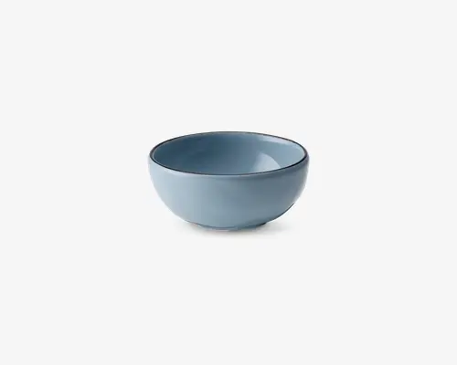 En lille, rund skål med en glat, mat lyseblå yderside og inderside. Skålens kant er en smule mørkere, hvilket giver en diskret kontrast. Skålen har et enkelt, minimalistisk design med blødt buede sider og en stabil bund.