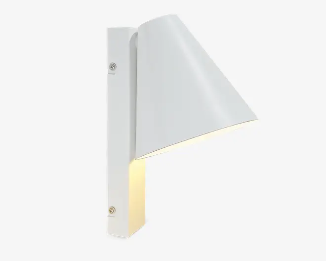 En moderne vægmonteret lampe med mat hvid finish. Designet har en lodret, rektangulær base med to synlige monteringsskruer og en konisk skærm, der leder lyset nedad. Skærmen er vinklet væk fra væggen og giver fokuseret belysning nedenunder. Lampen har rene linjer og et minimalistisk udtryk, der passer til moderne indretning.