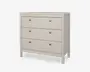 En lys beige kommode med tre rummelige skuffer, hver udstyret med to runde metalgreb for nem åbning. Kommoden har et enkelt, moderne design med rene linjer og en flad top, understøttet af fire solide ben. Overfladen er glat og mat, hvilket giver et moderne udtryk, der passer til forskellige rumtyper.