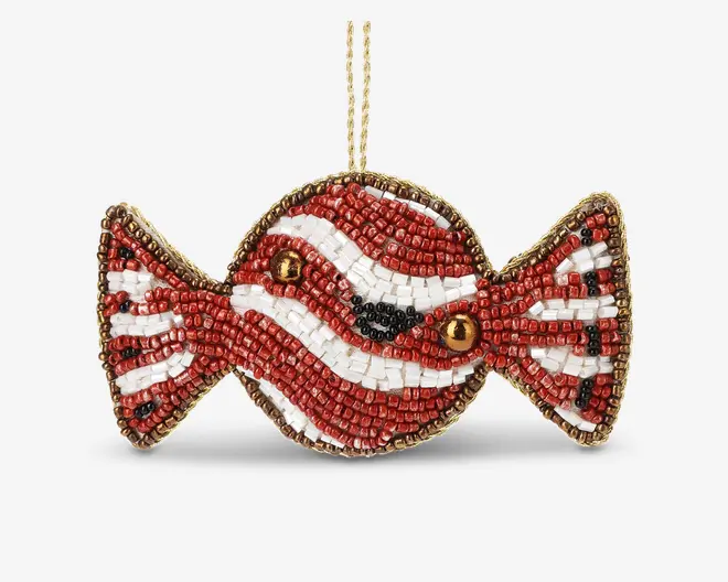 Pynt formet som et indpakket stykke slik, dekoreret med små perler i rød, hvid, sort og guld. Perlerne er arrangeret i bølgede striber, hvilket giver et festligt, pebermynteagtigt udseende. Kanterne er omkranset af guldfarvede perler, og der er en guldfarvet ophængssnor øverst.