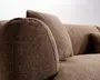 Nærbillede af en brun, tekstureret polstret sofa med afrundede armlæn og bløde ryghynder.
