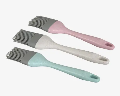 Sæt med tre silikonepensler med bløde, fleksible børster og ergonomiske håndtag. Hver pensel har et forskelligt pastelfarvet håndtag—lyserød, offwhite og lyseblå—med en let plettet overflade og hul for enden til ophængning. Børstedelen er grå og sidder solidt fast på håndtaget for nem rengøring og holdbarhed.