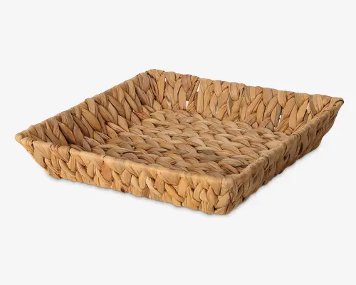 Firkantet bakke med høje kanter, lavet af tykke, tæt flettede naturfibre. Overfladen og siderne har en kraftig, flettet struktur, hvilket giver et rustikt og solidt udtryk. Farven er varm, lysebrun med lette nuancer, der fremhæver det naturlige materiale.