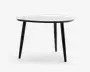 Moderne rundt bord med en glat, hvid bordplade og tre skrå, sorte ben. Designet er minimalistisk med rene linjer og en mat finish, hvilket gør det velegnet til moderne indretning. Bordet fremstår solidt og funktionelt, ideelt til små spiseområder eller som et accentmøbel.