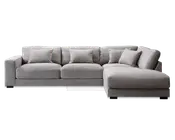 Moderne hjørnesofa i lysegråt stof med højrevendt chaiselong. Sofaen har brede, lavprofilerede armlæn og dybe sæder for ekstra komfort. Den leveres med fem matchende ryghynder, som giver ekstra støtte og et blødt, indbydende udtryk. Betrækket har en diskret tekstur, og det samlede design er enkelt og moderne, velegnet til rummelige stuer.