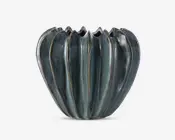 En dekorativ keramisk beholder med blank, mørkegrøn glasur og lodrette riller, der giver et bølget, blomsterlignende udseende. Kanten er ujævn og bølgende, hvilket tilføjer et unikt, organisk præg. Overfladen har diskrete farvevariationer, som giver et håndlavet udtryk.