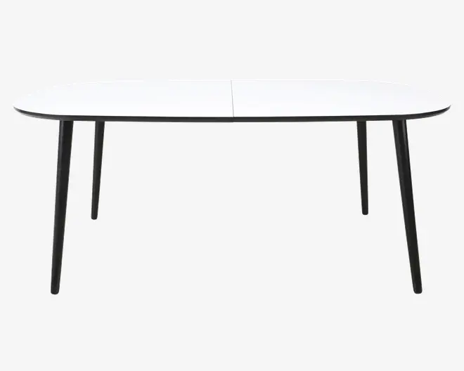 Et moderne bord med en glat, hvid rektangulær bordplade med let afrundede kanter. Bordet har fire slanke, skråtstillede ben i sort metal, hvilket giver et minimalistisk og stabilt udtryk. Bordpladen fremstår sømløs med en diskret linje i midten, hvilket muligvis indikerer, at bordet kan udvides eller foldes.