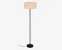 Høj gulvlampe med slank sort stander, rund sort fod og en lys beige plisseret skærm i tromleform.
